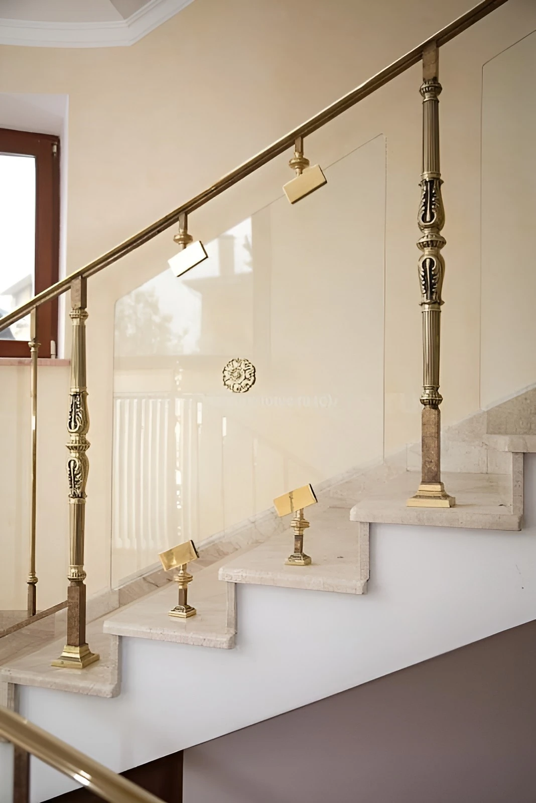 brass and glass stair railing with ornate brass balusters on a marble staircase