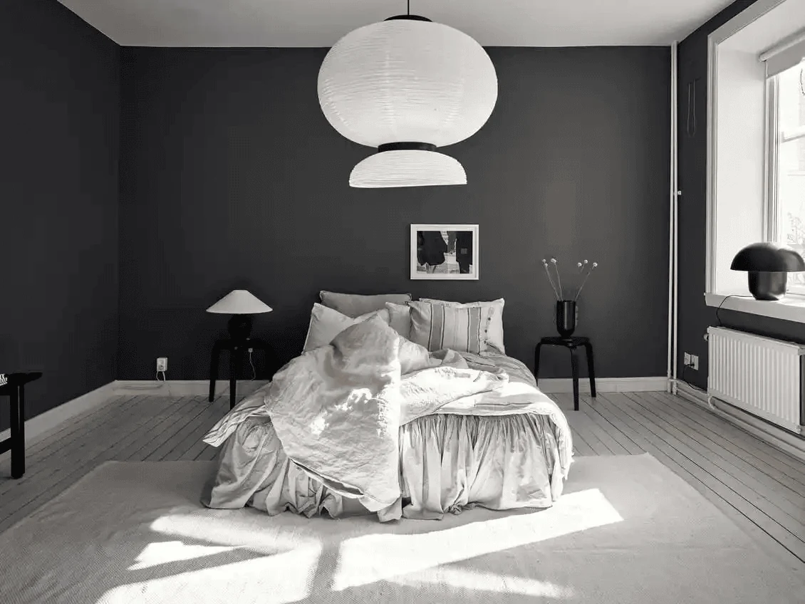 charcoal grey dark bedroom with white linen bedding and pale timber flooring