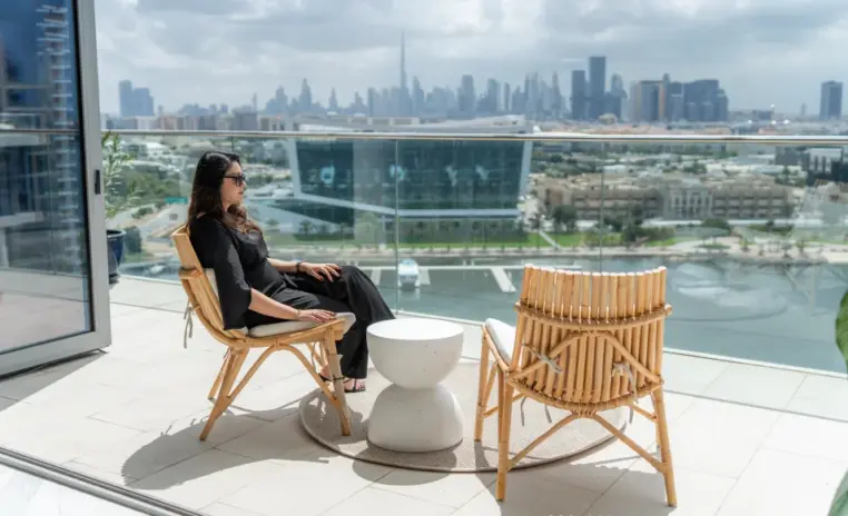 woman seated on a balcony with the city skyline behind