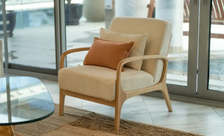 cream armchair with a wooden frame beside a window