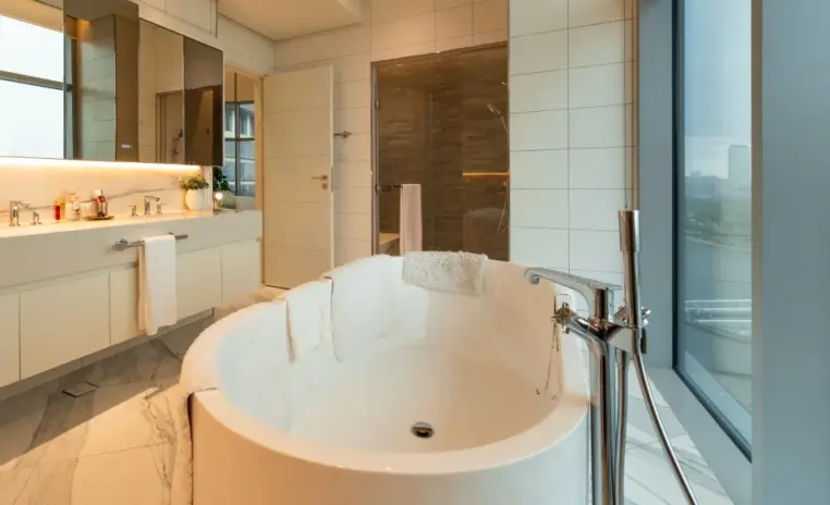 bathroom with a round freestanding bathtub beside a window