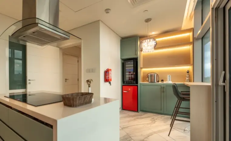 modern kitchen with sage green cabinets and a red fridge