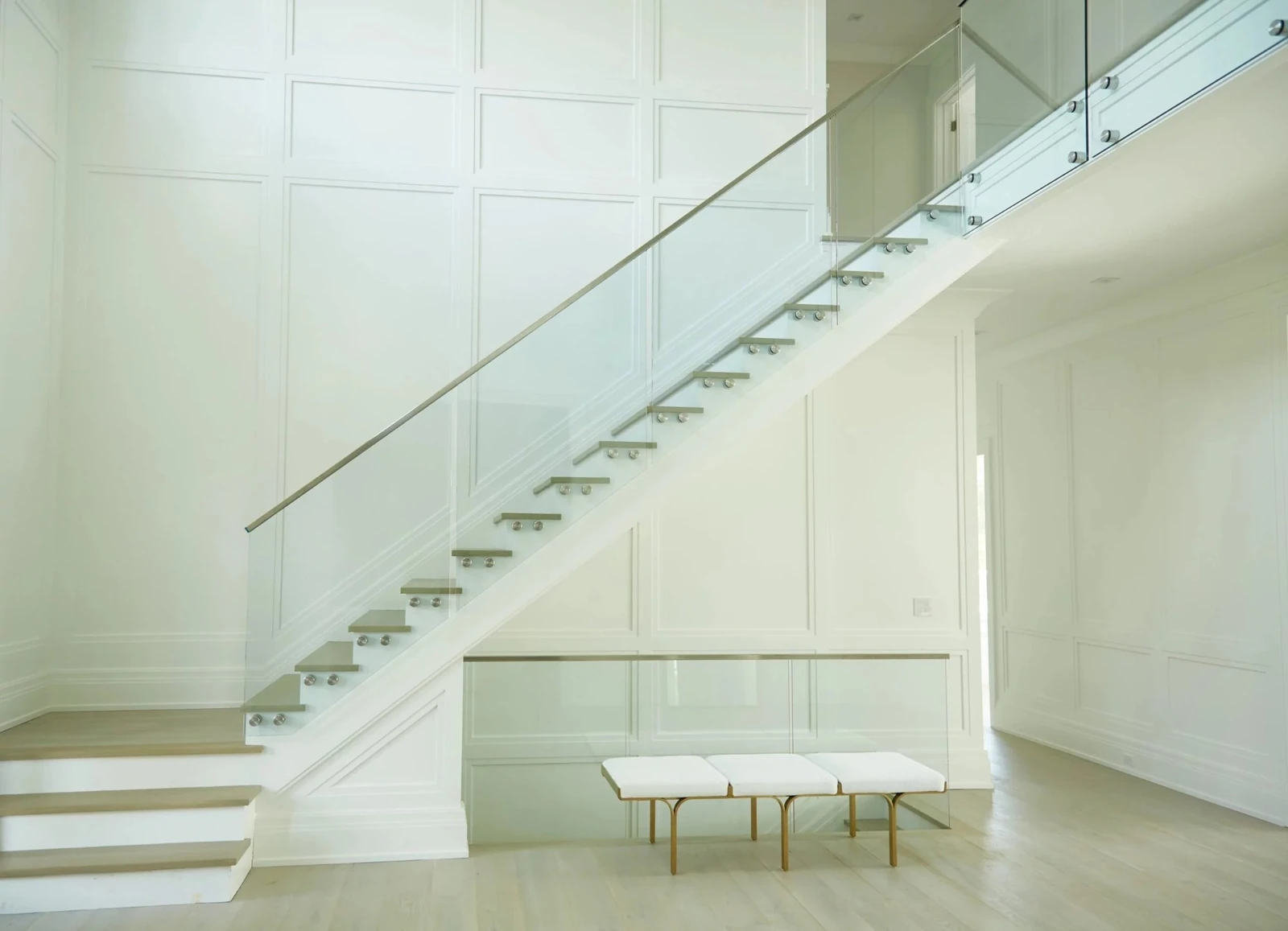 frameless glass stair railing on a panelled white staircase letting light through