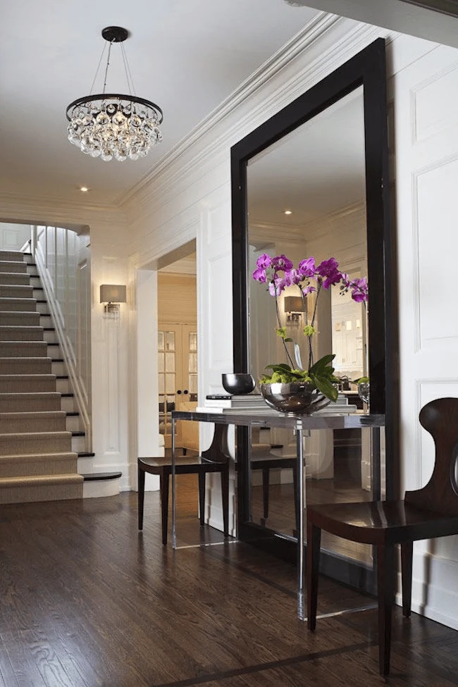 modern foyer design using an oversized mirror to brighten a dark entrance