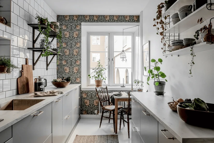 galley kitchen with a dark botanical feature wall in kitchen wallpaper beside white tiles